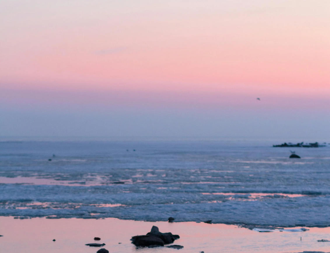 A calm sea beneath a pink sky